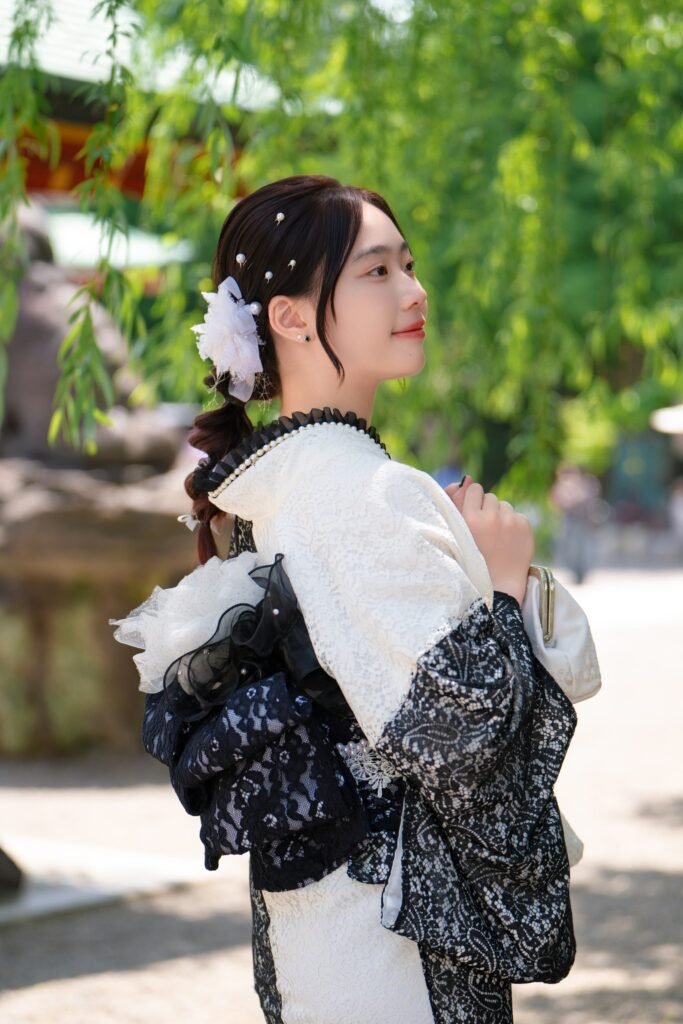 Woman in modern lace kimono with lace and floral hairpiece, looking serene outdoors at asakusa