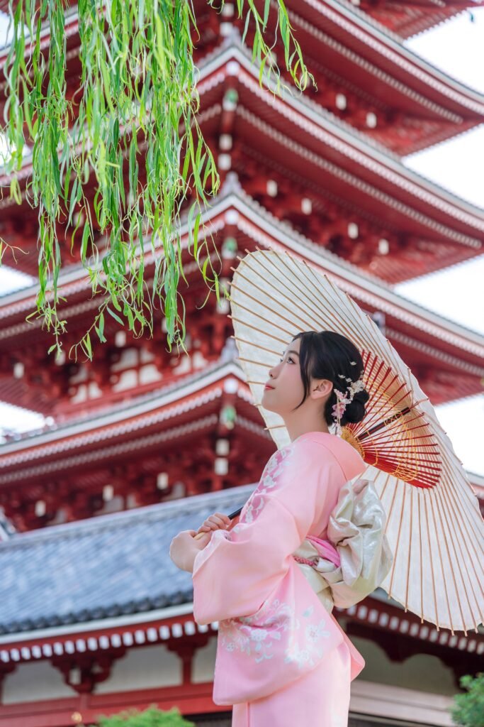 Woman in pink kimono with parasol under cherry blossoms at Asakusa
