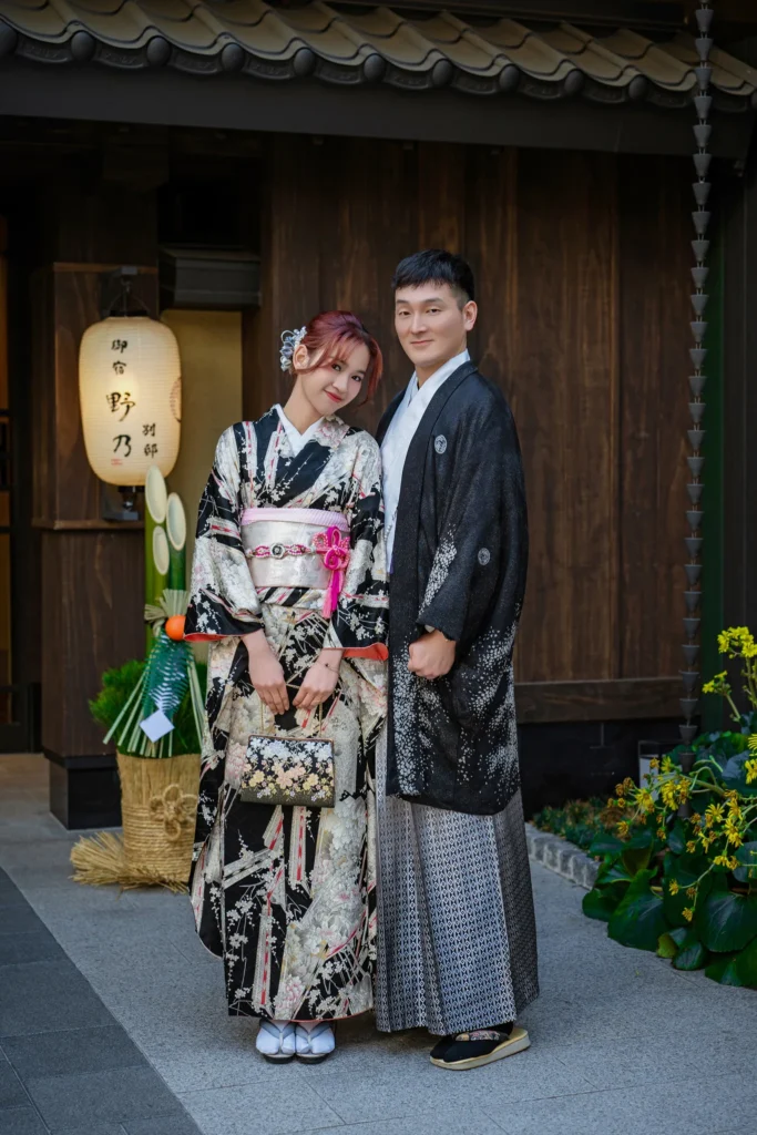 Couple in premium furisode and men's montsuki hakama at Sensoji Temple, Asakusa Tokyo — paper lantern in background