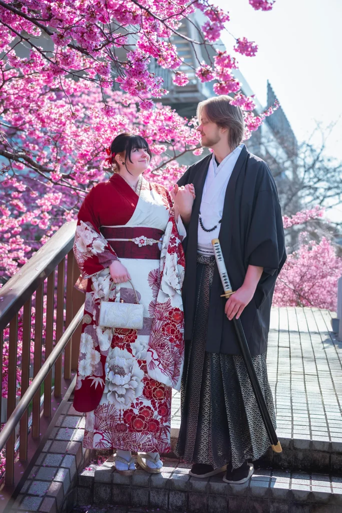 Couple in premium furisode and men's montsuki hakama at Sumida River, Asakusa Tokyo — man holding katana