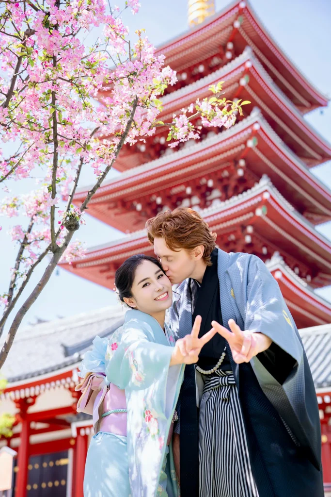 Couple in traditional kimono rental at Sensoji Temple, Asakusa Tokyo — cherry blossoms and five-story pagoda in background