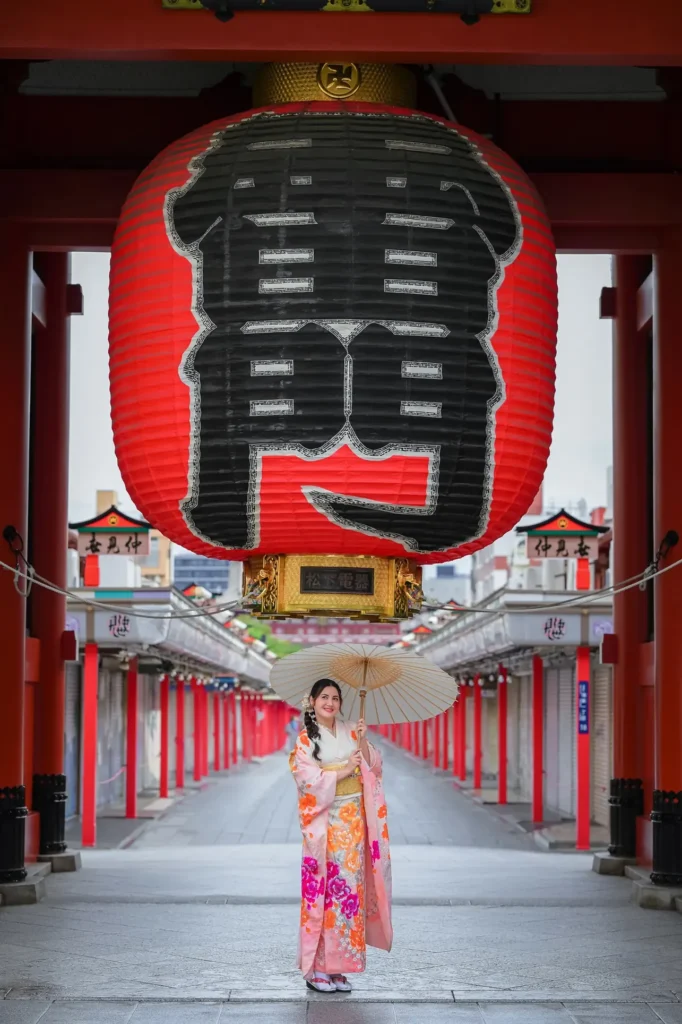 Guest in a pink floral kimono under the Kaminarimon lantern, empty Nakamise street with shutters still closed