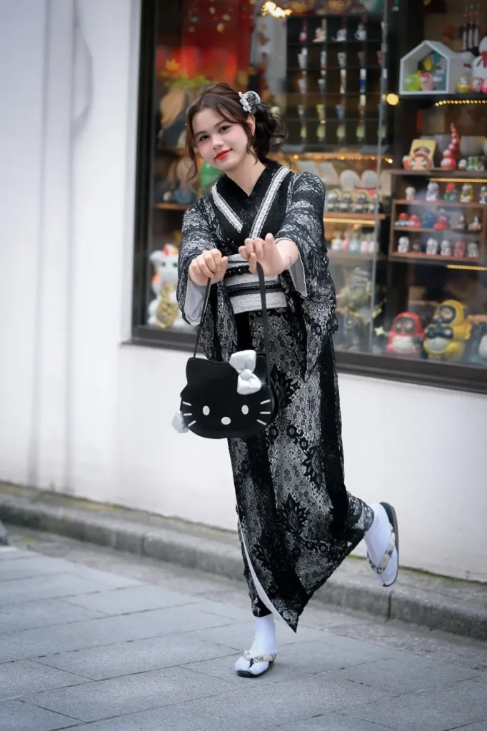 Girl in a black lace kimono walking with a white Hello Kitty face handbag in Asakusa, Tokyo