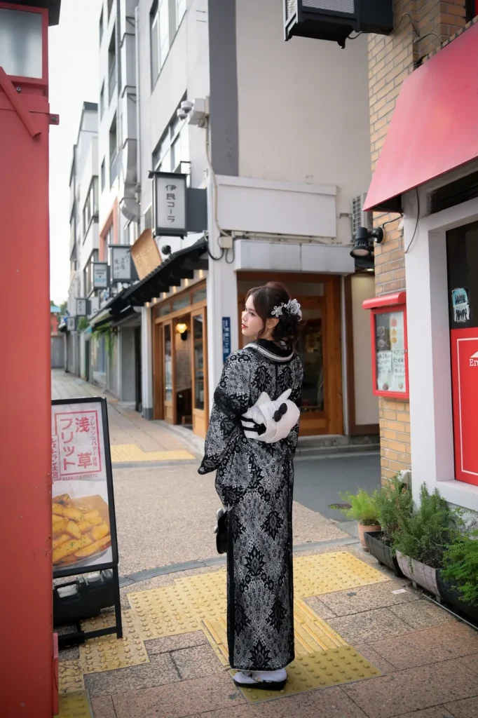 Girl in a black and white lace kimono carrying a Hello Kitty handbag on a shopping street in Asakusa, Tokyo