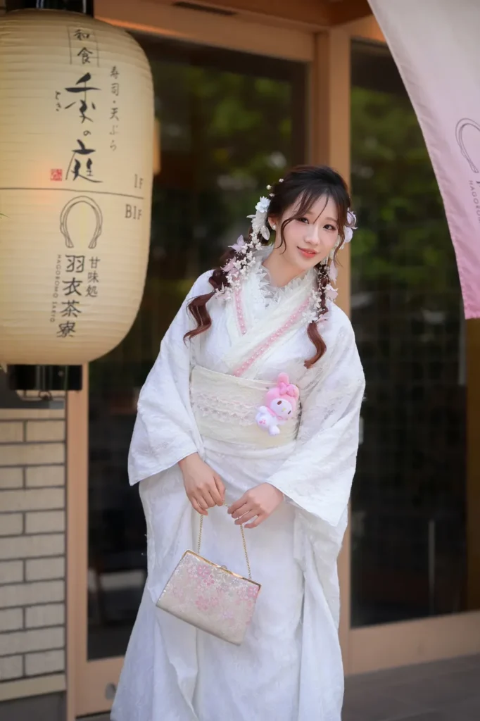 Girl in a white lace kimono with a My Melody plush tucked into her obi beside a Japanese paper lantern in Asakusa