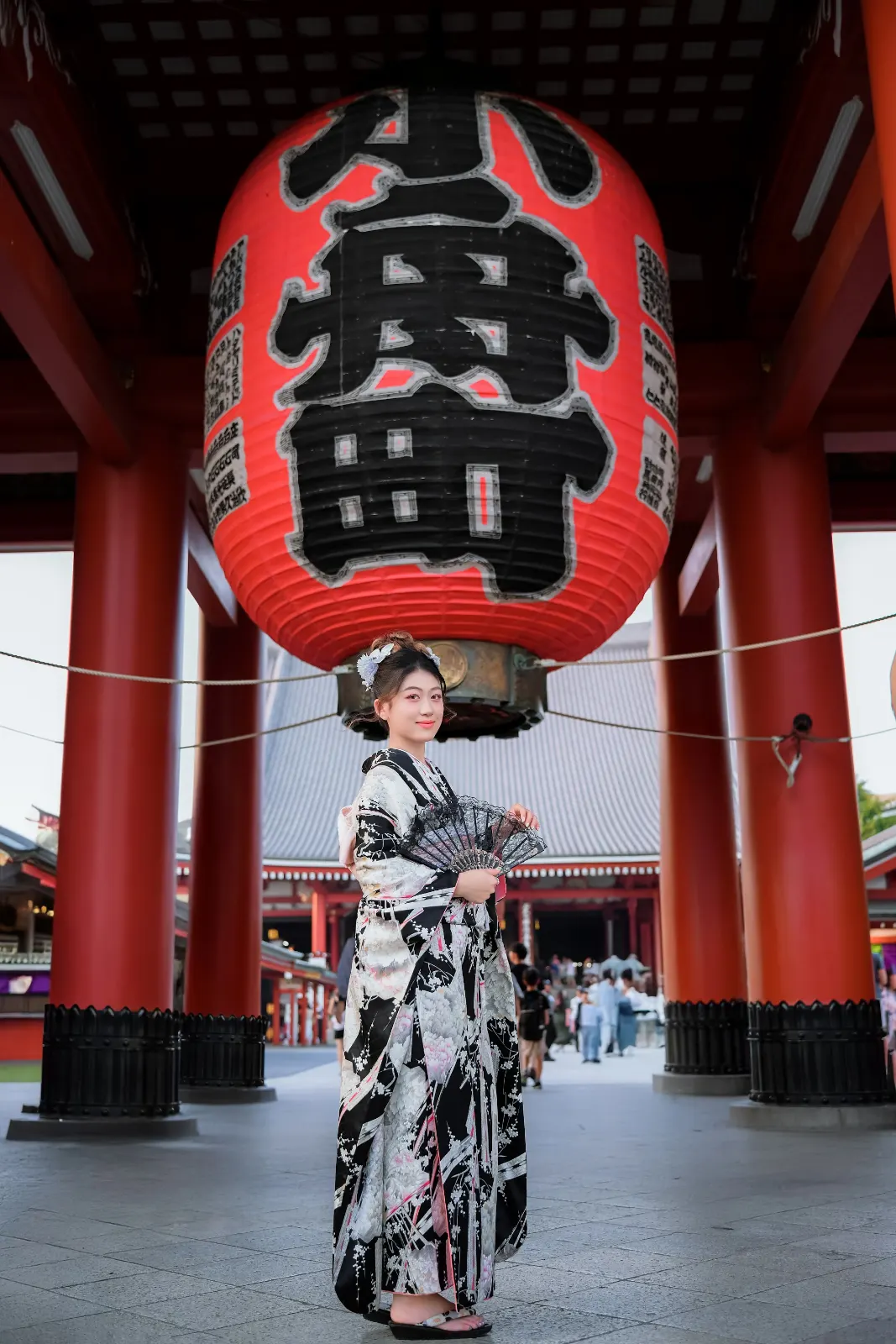 Guest in a black and white kimono beneath the giant red lantern of Hozomon Gate at night