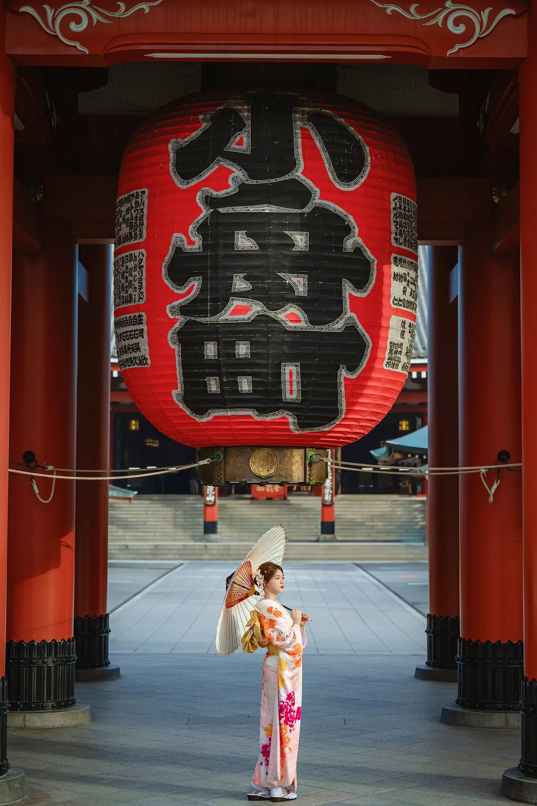 Woman in kimono with a paper umbrella under the giant red lantern of Hozomon Gate in the early morning, Asakusa