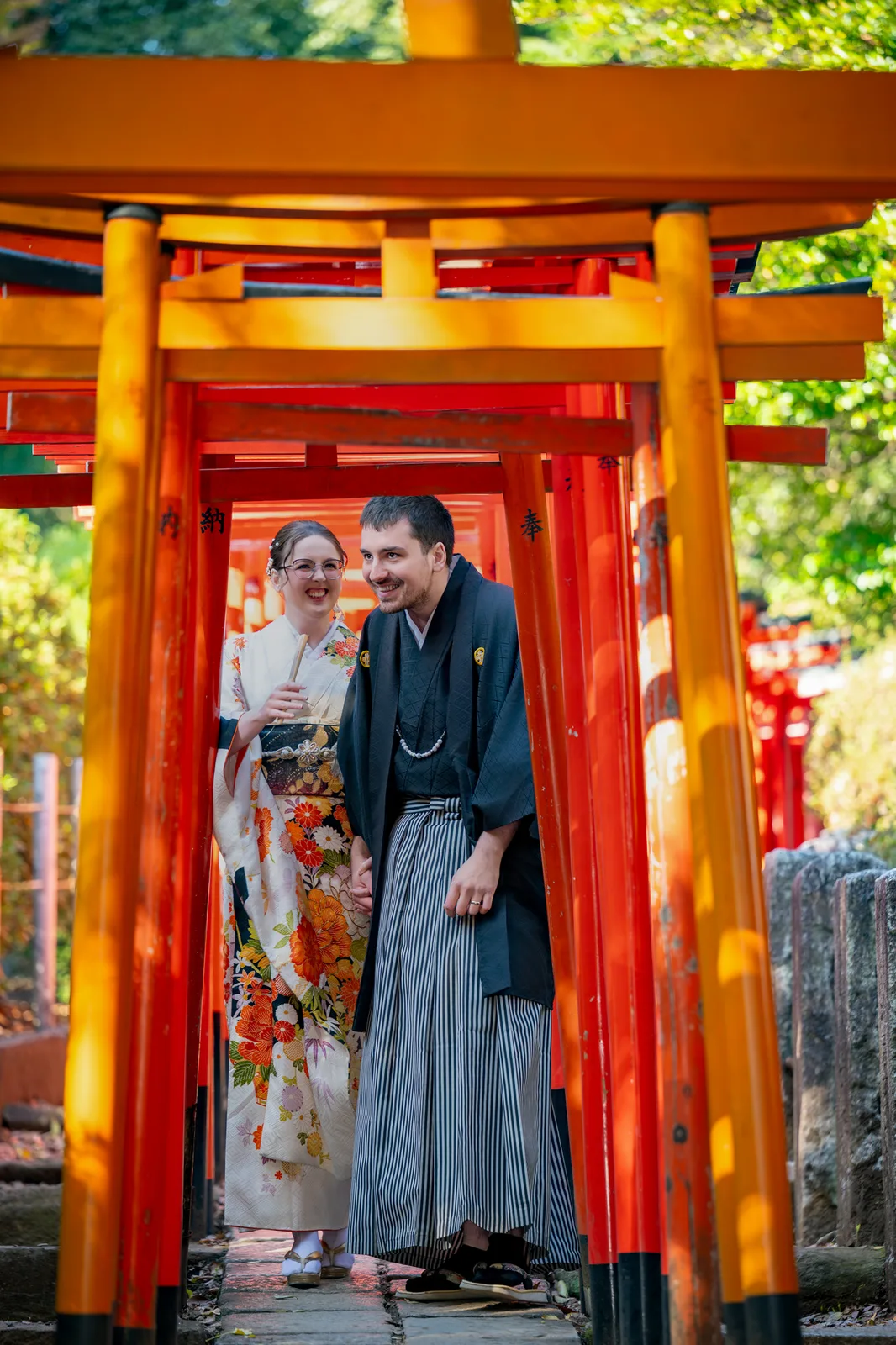 Couple in kimono standing inside the vermilion torii gate tunnel at Nezu Shrine