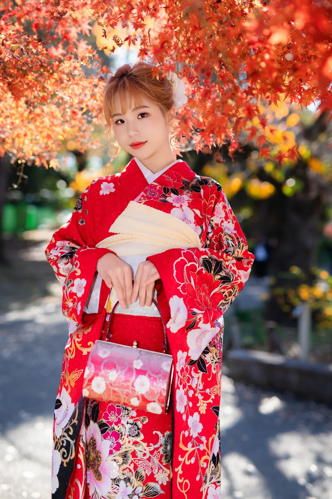Woman in red furisode under red maple leaves in Ueno Park, Tokyo