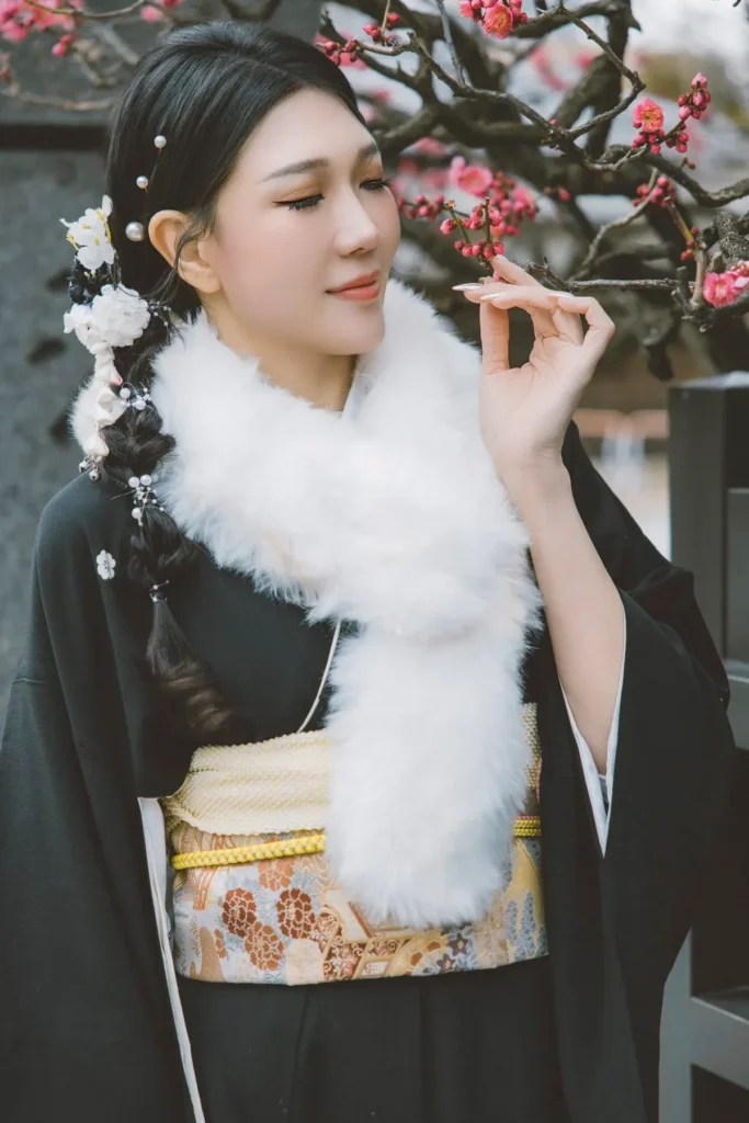 Black kimono with a white fur shawl and gold obi among plum blossoms in Asakusa in February