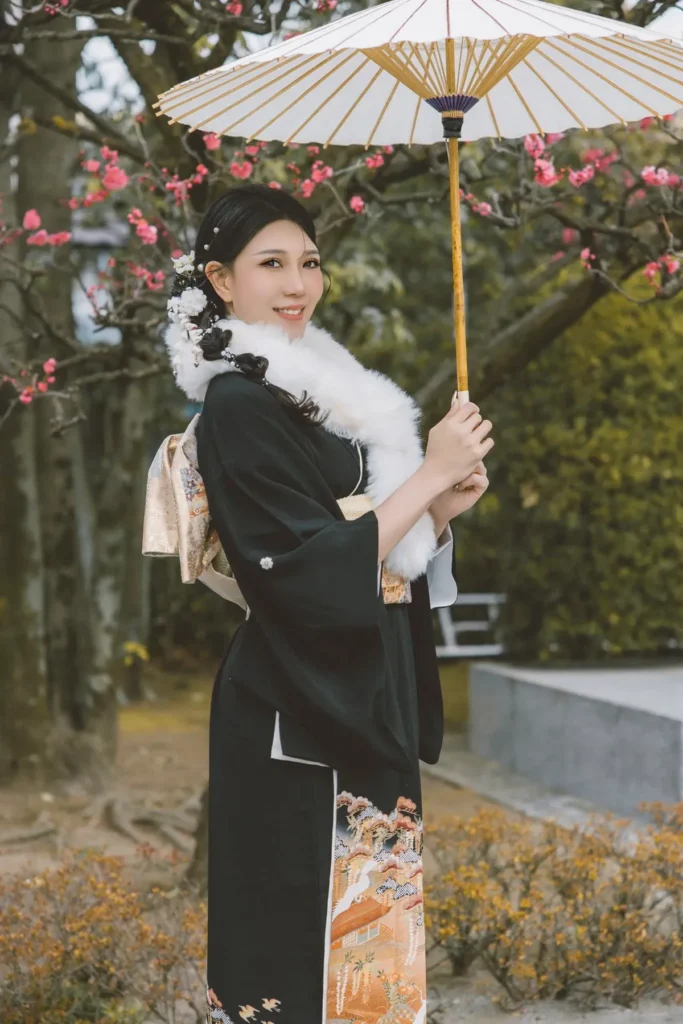 Black kimono, white fur shawl and paper parasol under plum blossoms in late winter in Asakusa