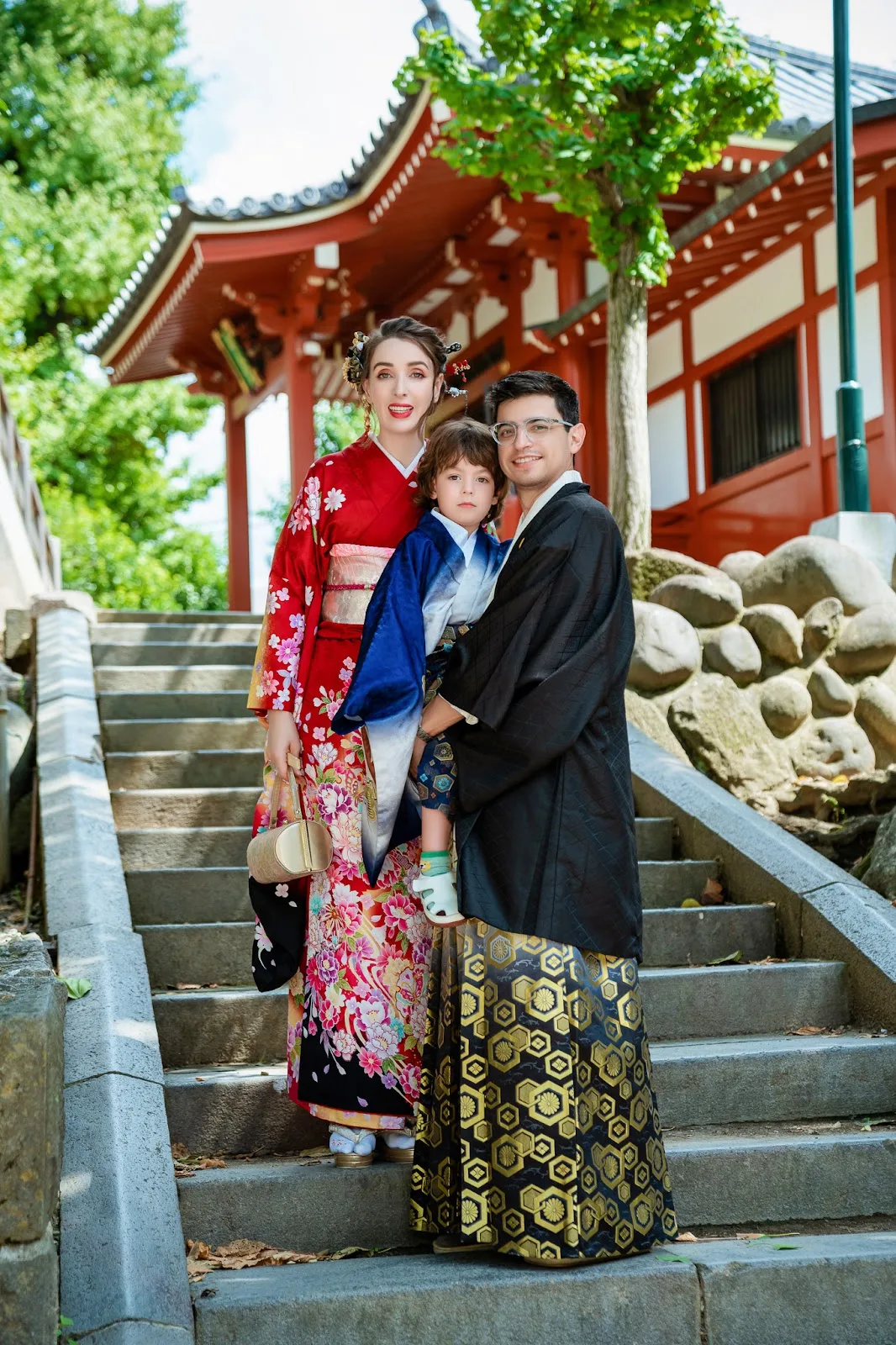 Family in kimono on the stone steps of a temple hall in Asakusa, father holding a toddler