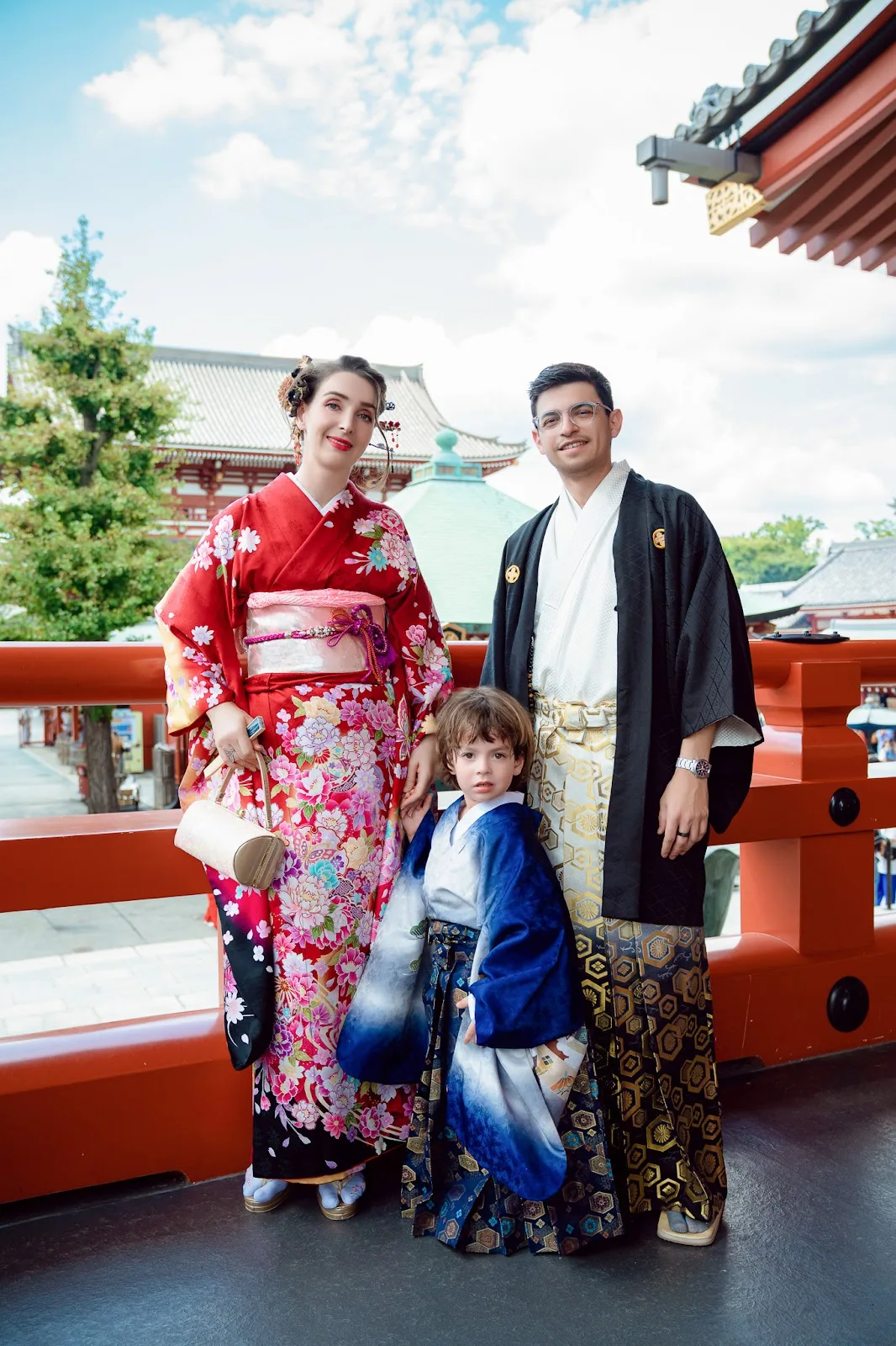 Parents in kimono with their toddler son by a red railing at Sensoji Temple, Asakusa