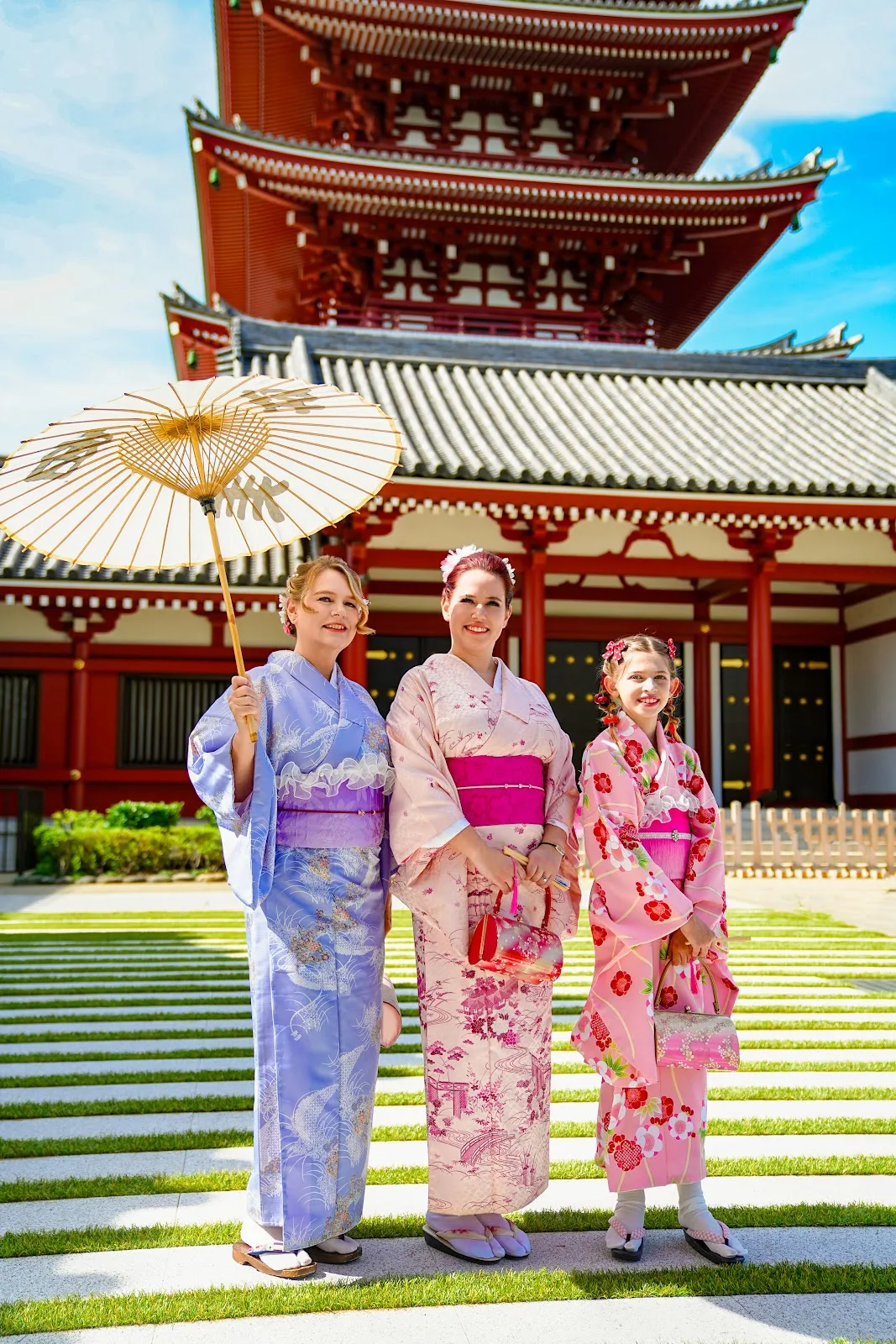 Three women of one family in kimono with a paper umbrella near the Five-Storied Pagoda