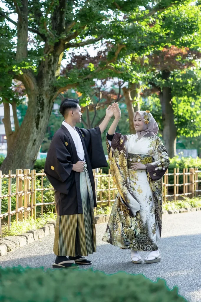 Couple in kimono and hakama in a garden in Asakusa, the woman in a beige hijab and black and gold kimono