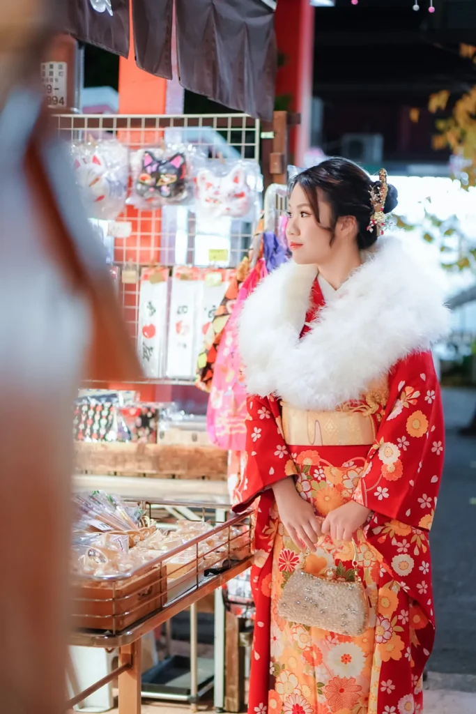 Red kimono with a white winter shawl browsing a souvenir shop during a winter kimono walk in Asakusa