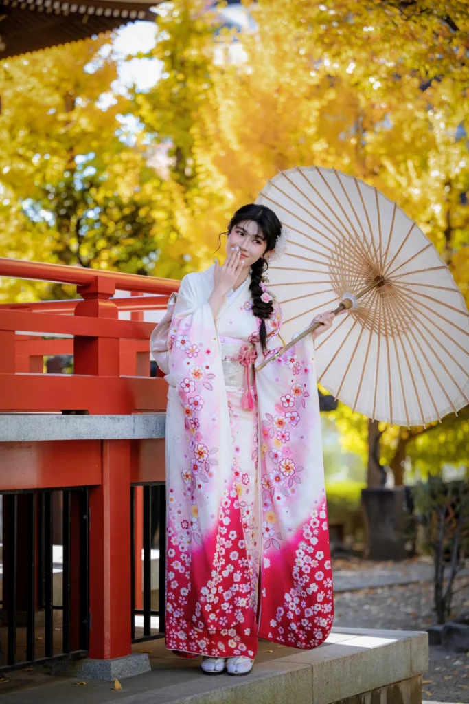 Pink and white furisode with a white parasol beside the red railing of Benten-dō in autumn, Asakusa