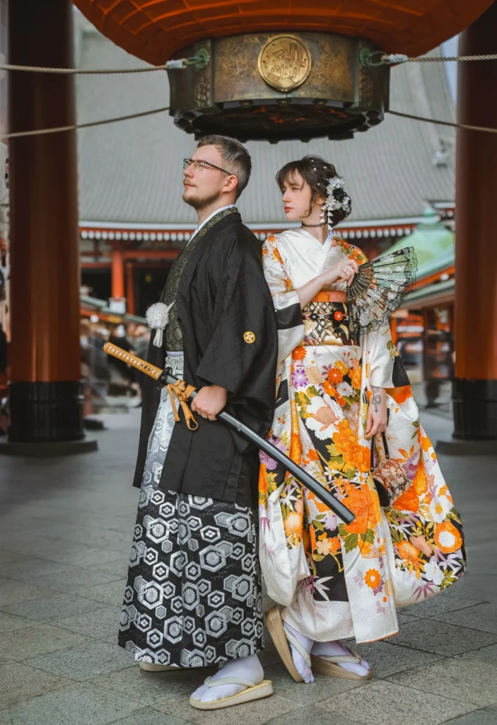 Couple in kimono and hakama beneath the hanging lantern of Hozomon Gate at Sensoji Temple