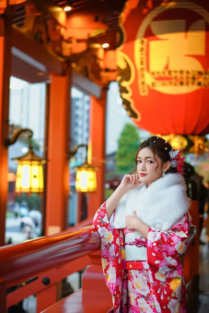 Guest in a red and pink kimono with a white fur shawl under red lanterns at Sensoji Temple in winter